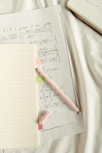Flat lay of handwritten mathematical formulas and notes with colorful sticky notes and pen.